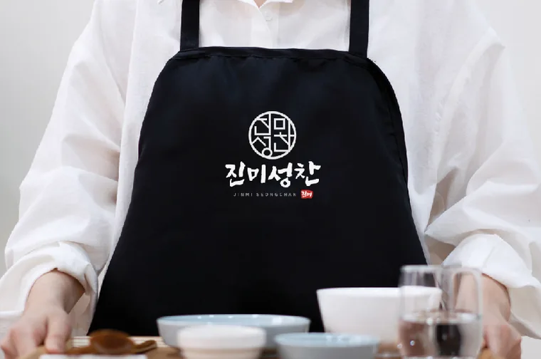 진미성찬 로고가 박힌 검정 앞치마